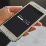 Tangan memegang smartphone yang sedang memuat koneksi jaringan